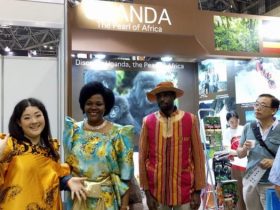 A Japanese lady smiles in a gomesi at the expo